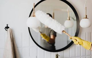personne qui nettoie un miroir avec un plumeau